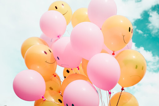 Pink and yellow balloons with smiley faces.